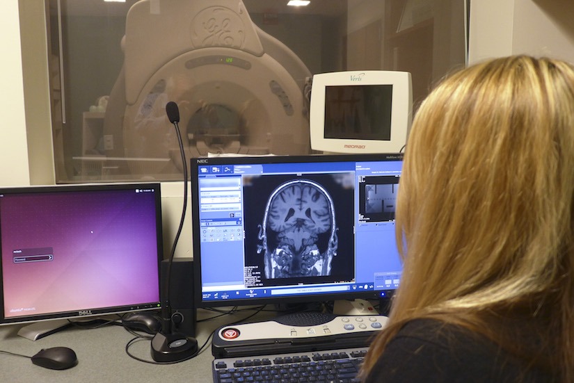 Sara John, an MRI research technologist at the UW School of Medicine and Public Health, reviews research images from a GE MR scanner, in the Wisconsin Institute of Medical Research on campus. Patient names have been blurred on the screen in this photo.