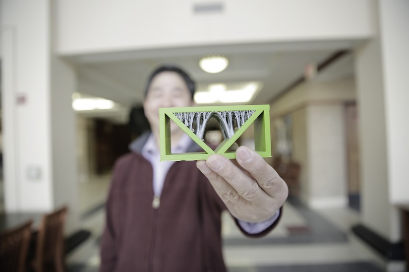 Photo of Xiaoping Qian holding a 3D-printed beam