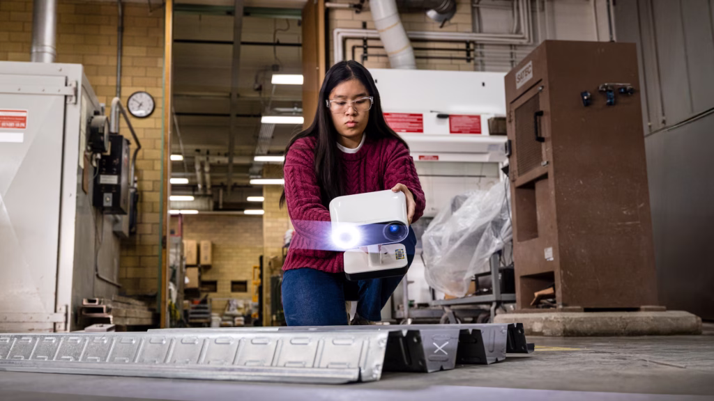 undergraduate showing research technique in structures lab.