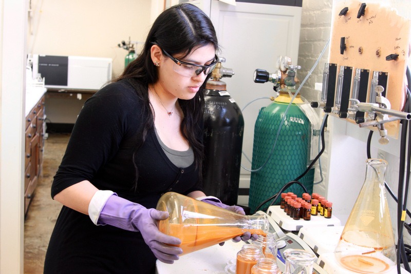 Student pouring orange liquid in lab
