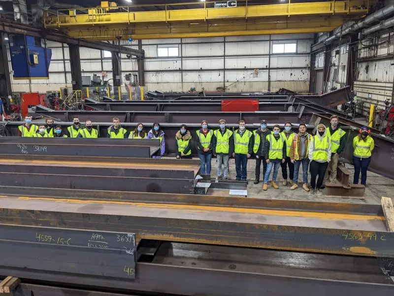 Students in warehouse of steel I-beams