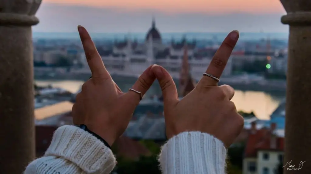 Fingers of student in W shape with foreign city in the background