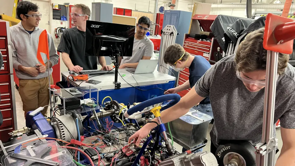 Students from the Wisconsin Autonomous team work in an automotive lab.
