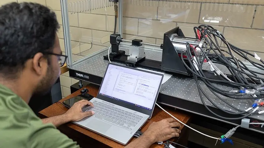 Student uses a laptop computer which is connected to a berringless motor in a clear, plastic enclosure