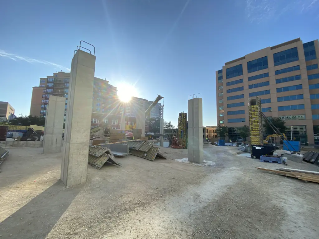 The sun rises over concrete columns on the construction site of a future hotel.