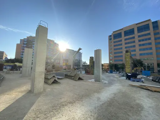 The sun rises over concrete columns on the construction site of a future hotel.