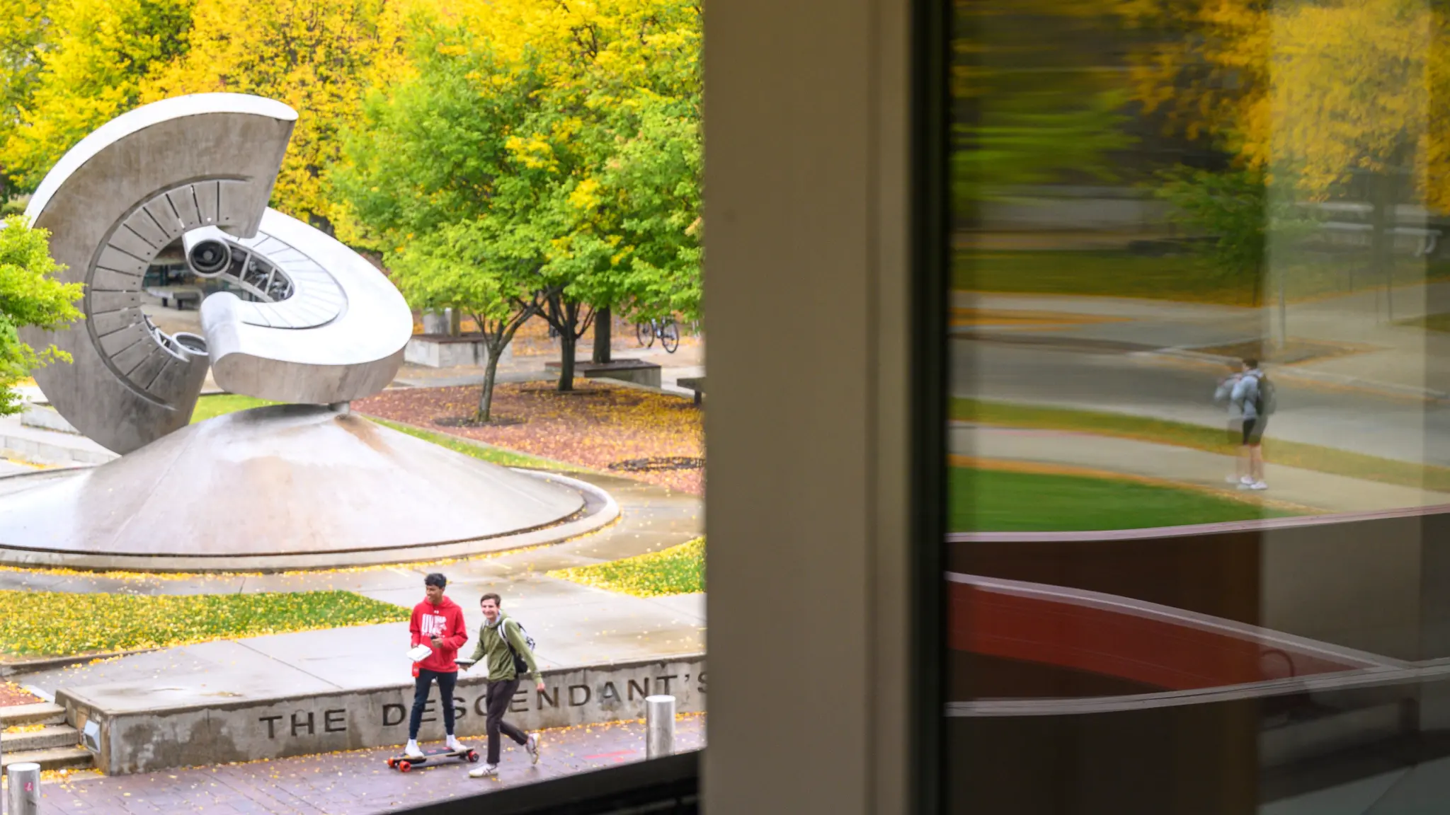 Students walk and skateboard in front of Engineering Hall during a mild and periodically rainy autumn day