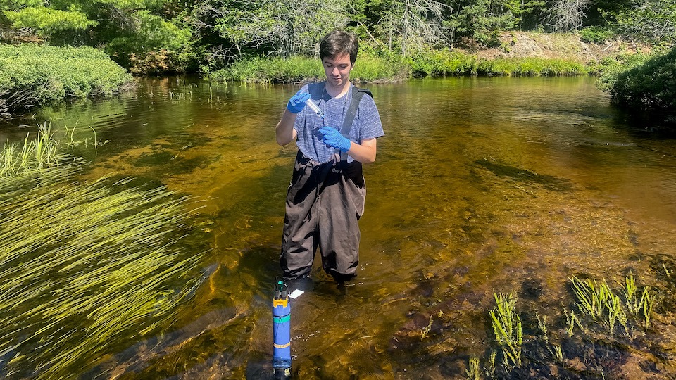 Graduate student Reid Milstead takes samples from a lake