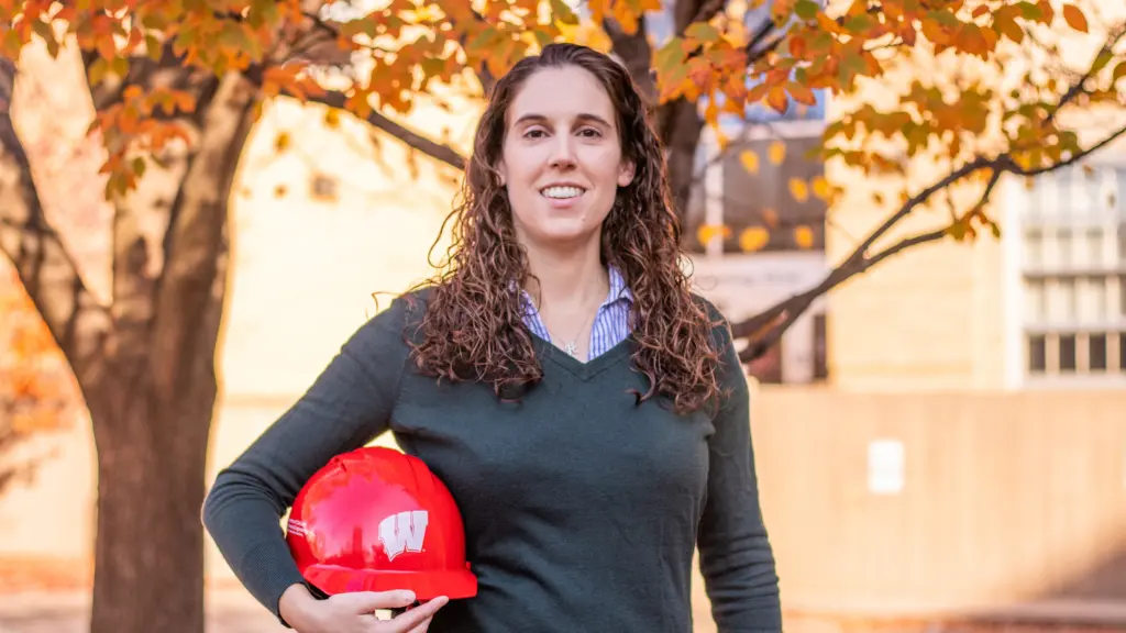 Professor Hannah Blum poses with a hard hat on a sunny fall day.