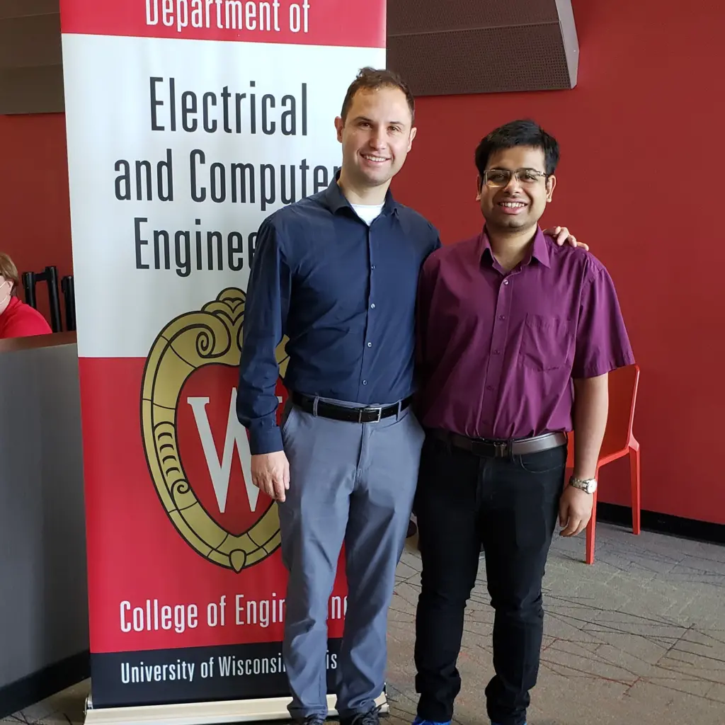 Professor Umit Ogras with student next to ECE banner