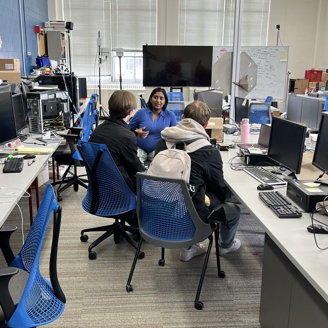 Bhuvana Krishnaswamy talks with students in a lab filled with computers