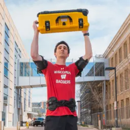 Tyler Bennett lifts a case overhead with help from an exoskeleton