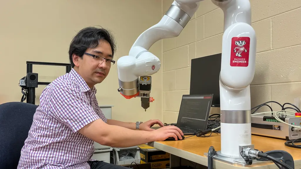 PhD student Weijun Shen works with a robotic arm