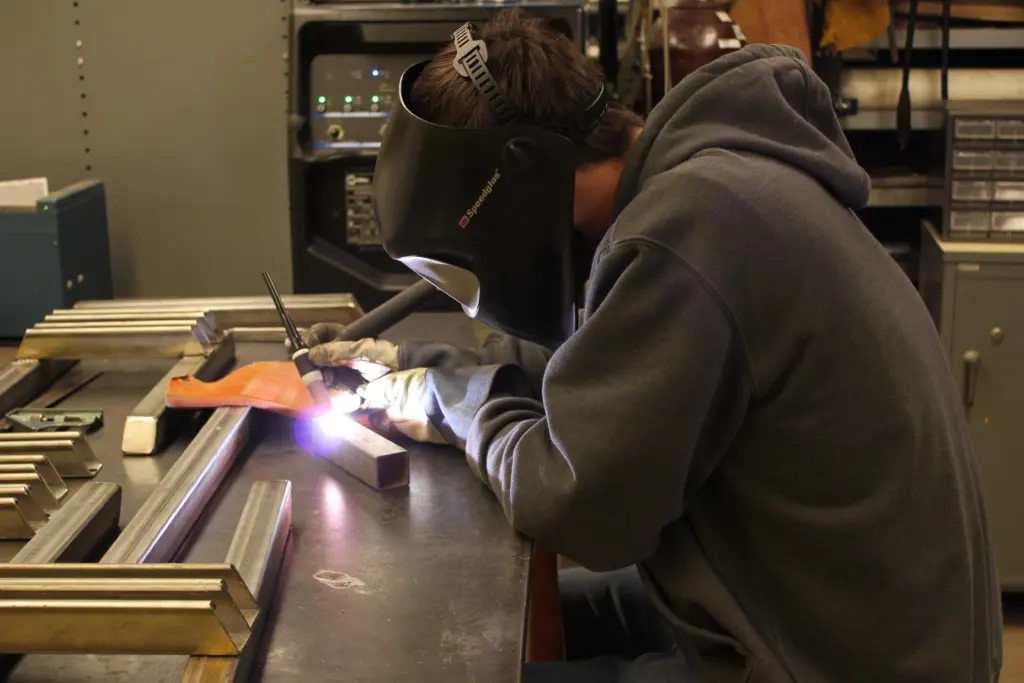 student welds pieces of metal together