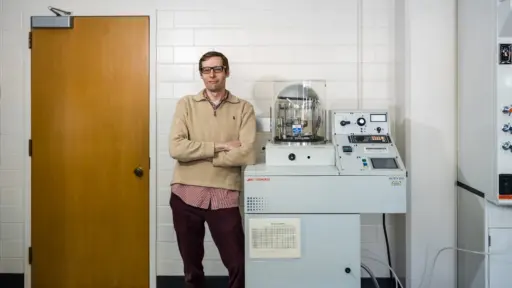 Theodore Puls poses next to the chemical vapor deposition system