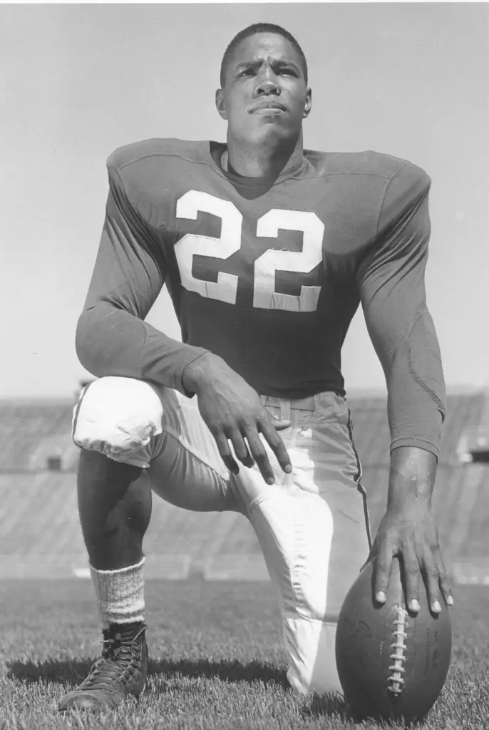 Sidney Williams kneeling on the field with football in hand.