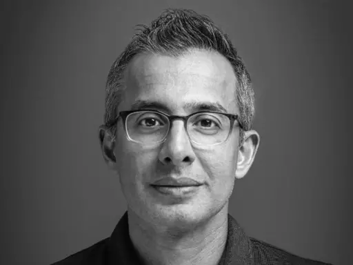 black and white professional headshot, very close-up, man wearing glasses