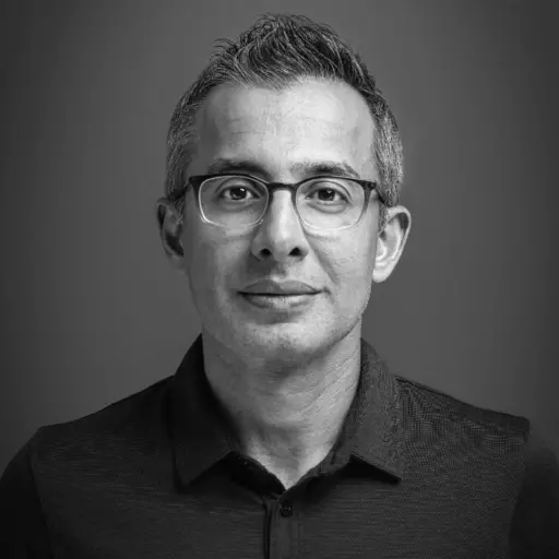 black and white professional head shot man wearing glasses and black button-up shirt