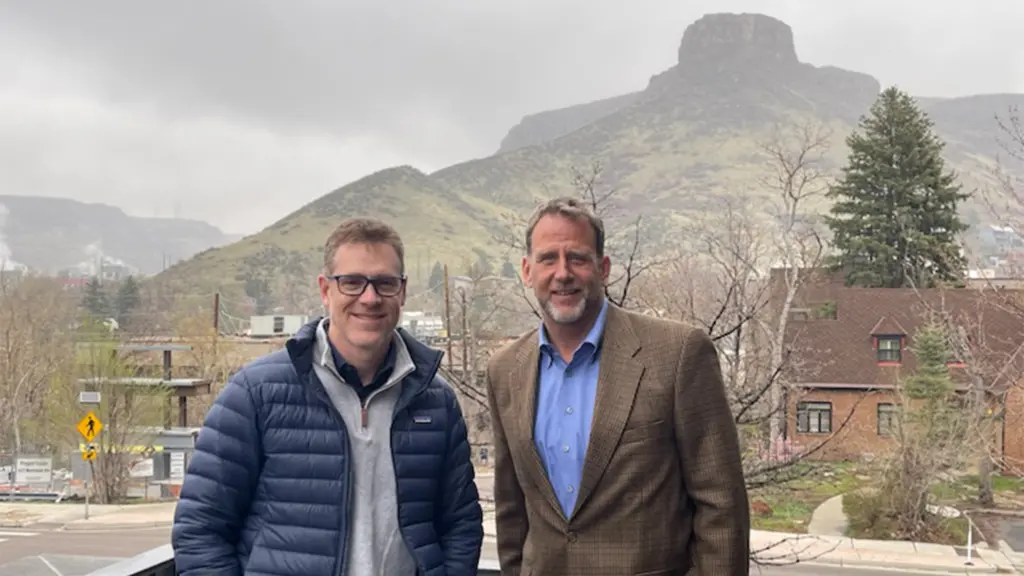 UW-Madison alumni Ryan Waddington and Michael Urynowicz pose in front of a mountain.