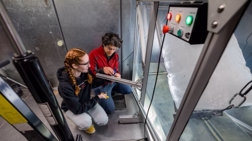 Nimish Pujara and a student set up a small camera outside of a wave tank