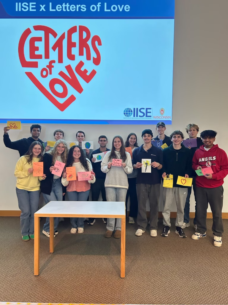 group of college students standing behind a table holding handmade cards and letters