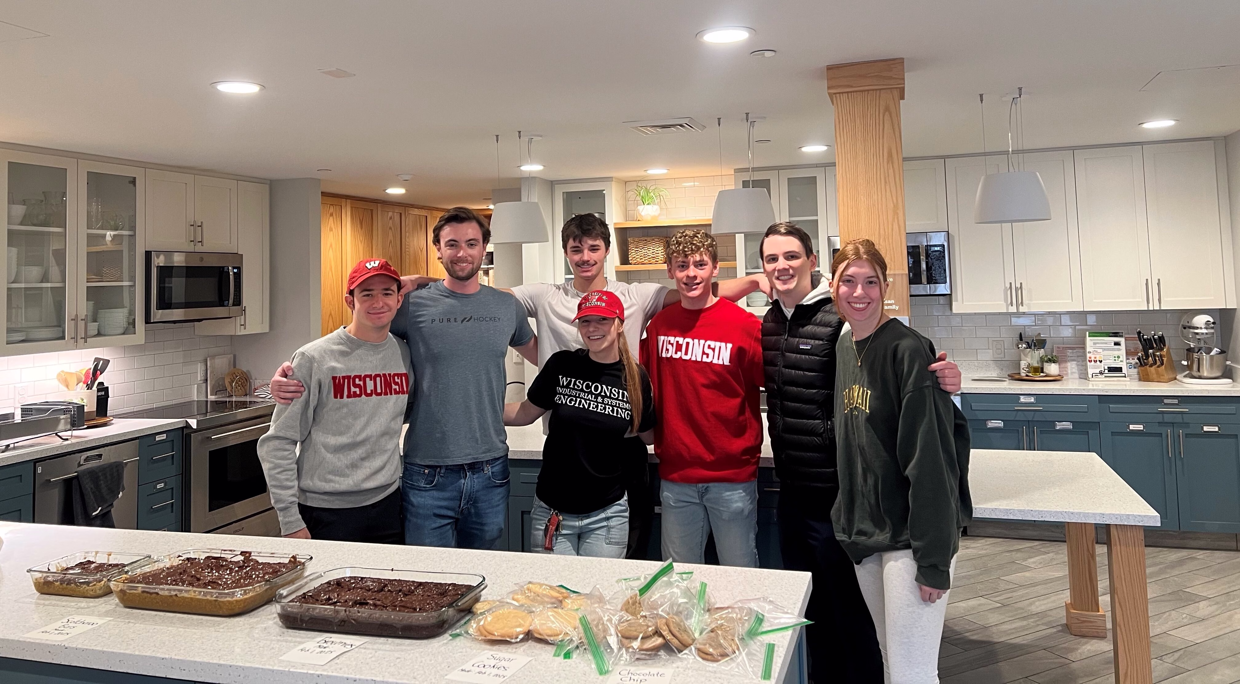 Group of students standing arm in arm behind a counter of food