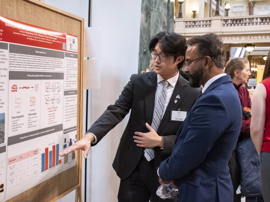 materials science and engineering student Leo Liu explains his research poster to an attendee at Research in the Rotunda