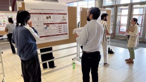 Two professors review two research posters with two graduate students