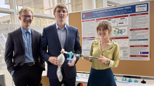 BME students Nicholas Symons, Calvin Duffy and Alice Hegeman holding their prototype in front of their poster titled "In-line HEPA filter bypass adapter: Enhancing ventilator safety and efficiency through innovative circuit management."