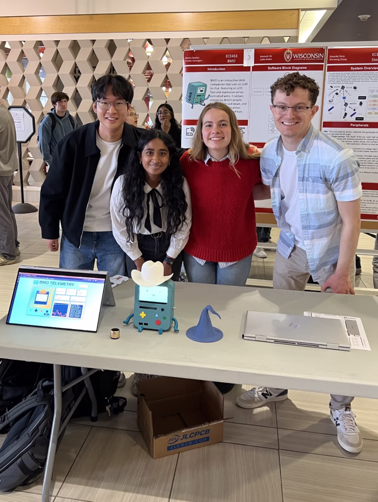Four students in front of a research poster standing behind a table with project