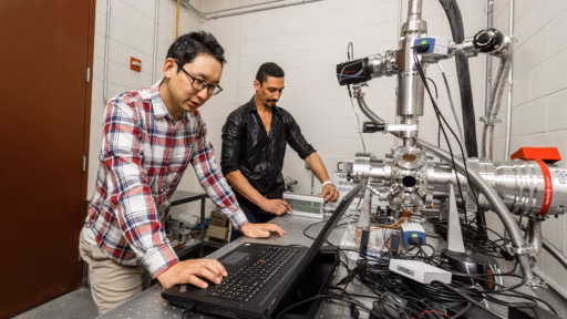 Graduate student Jiandong Yuan (left) and Luis Escano work with the electron beam melting system