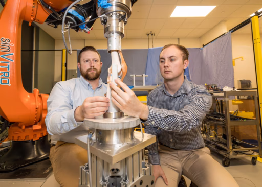 Assistant Professor Josh Roth (left) and a student work with a robotic testing system in Roth's lab