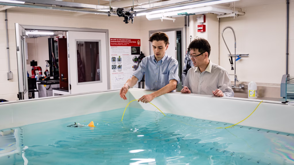 PhD student Jack Stonecipher and Assistant Professor Wei Wang watch a robotic fish swim