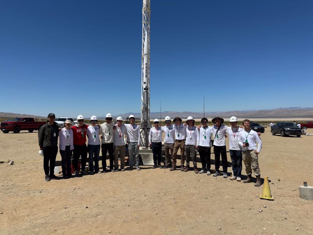 15 students standing in front of rocket