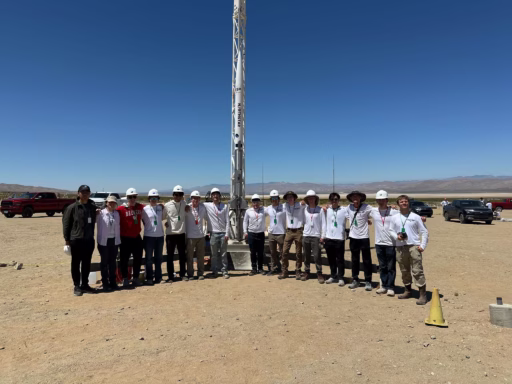 15 students standing in front of rocket