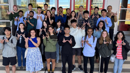 Group of around 30 ECE PhD students standing on steps in front of building