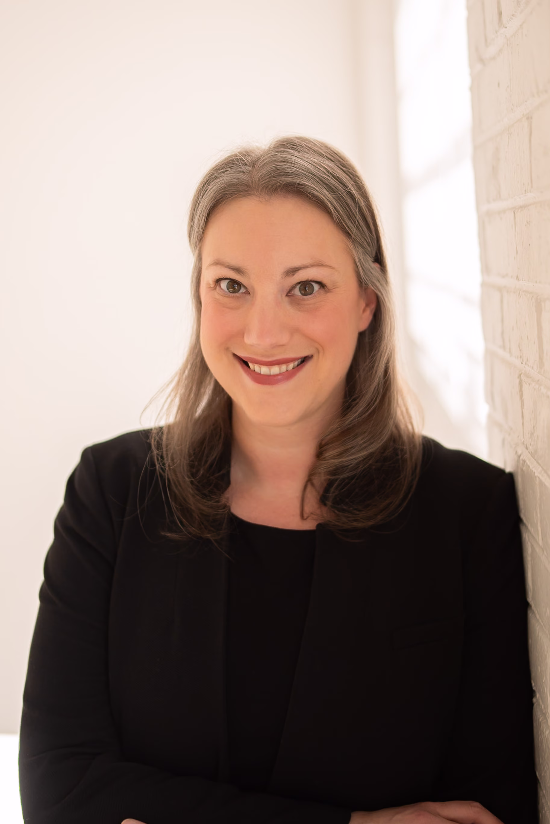 Headshot of Laurel Hind. She has dirty blonde hair and is wearing a black blazer.
